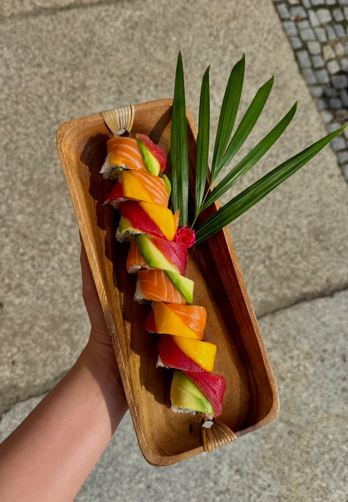 Kolorowa rolka z łososiem, tuńczykiem, mango i awokado na drewnianej tacy