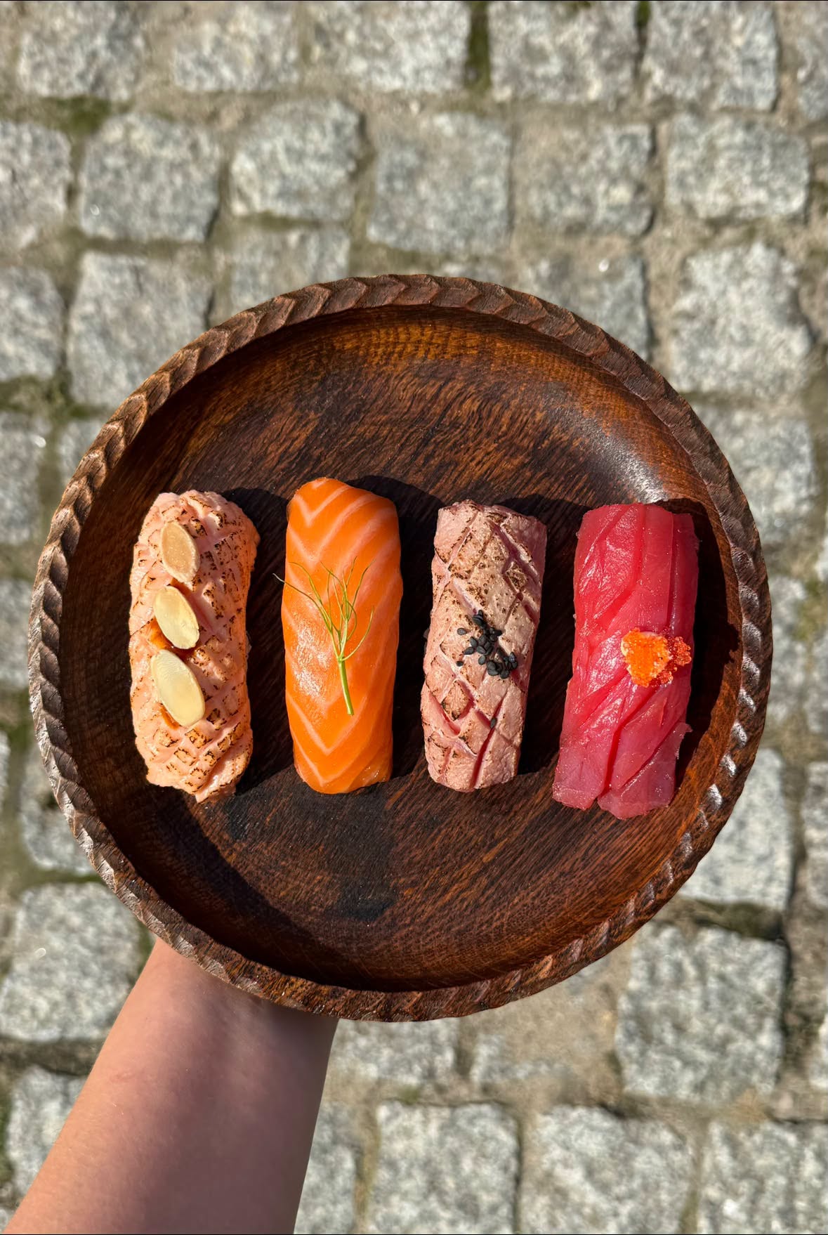 Cztery nigiri z łososiem i tuńczykiem, surowe i opalane, na drewnianym talerzu